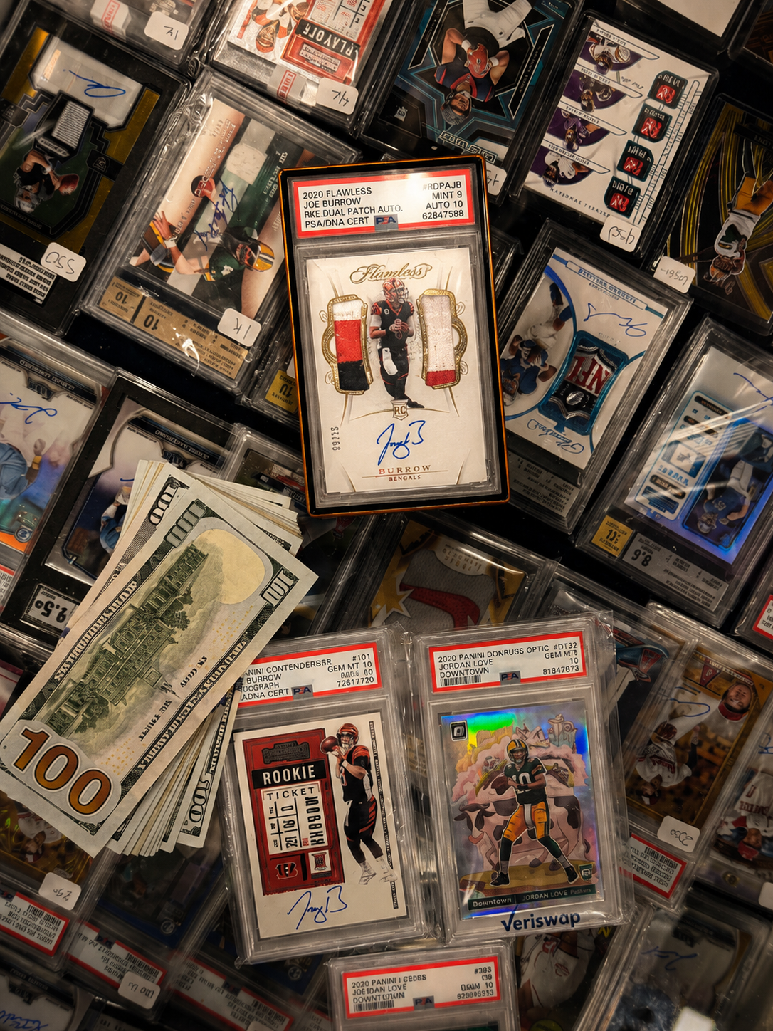 The Joe Burrow Flawless slab in a showcase surrounded by other graded cards and a stack of hundred-dollar bills at the Dallas Card Show